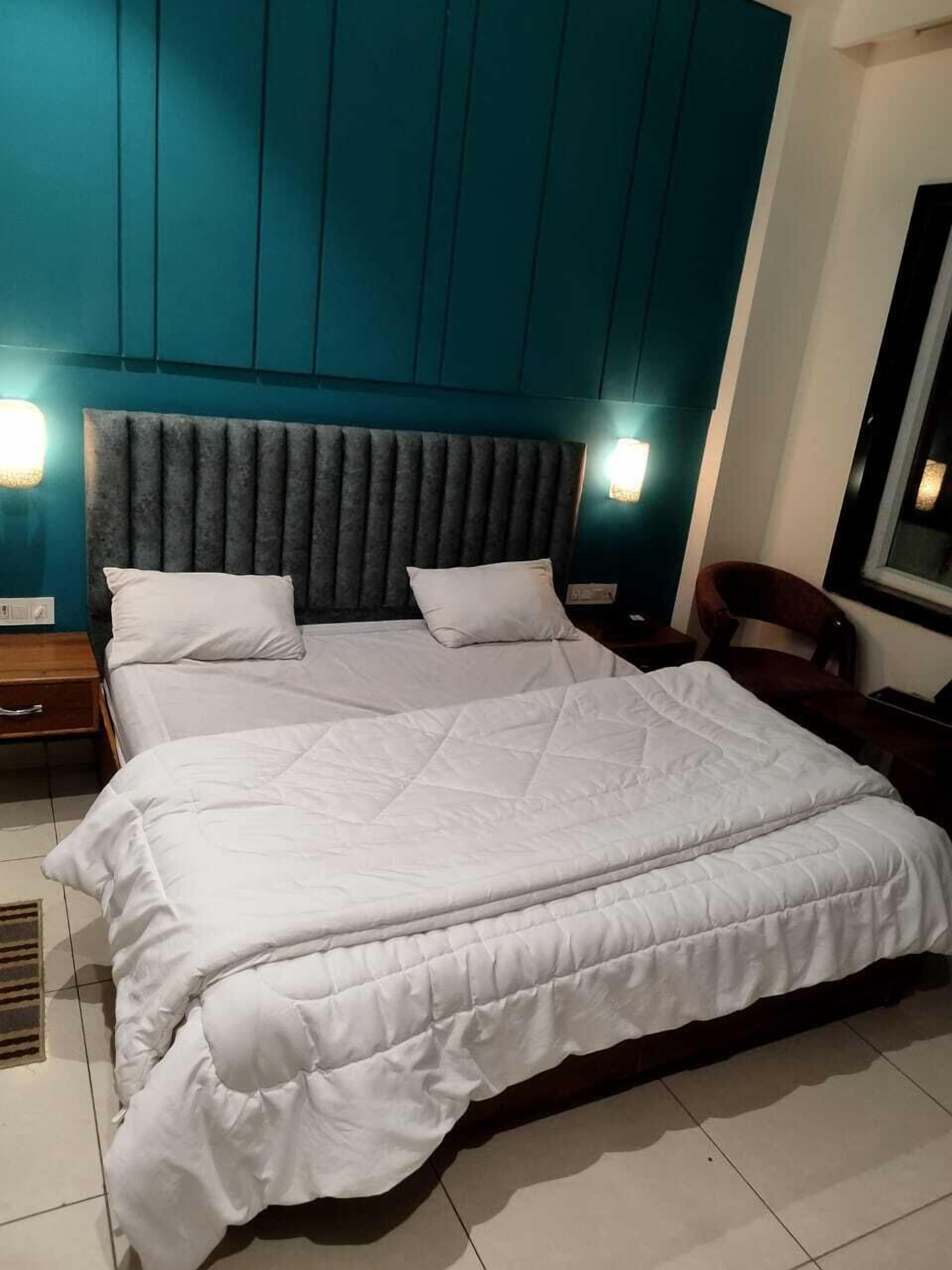 A large bed with a quilted white duvet, a padded headboard, and two bedside lamps.