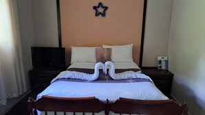 Una cama bien tendida con un adorno de estrella en la cabecera, una cabecera de madera y una mesita de noche con un cartel.