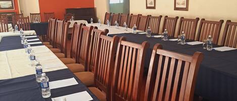 A conference room with long tables, chairs, water bottles, and papers.