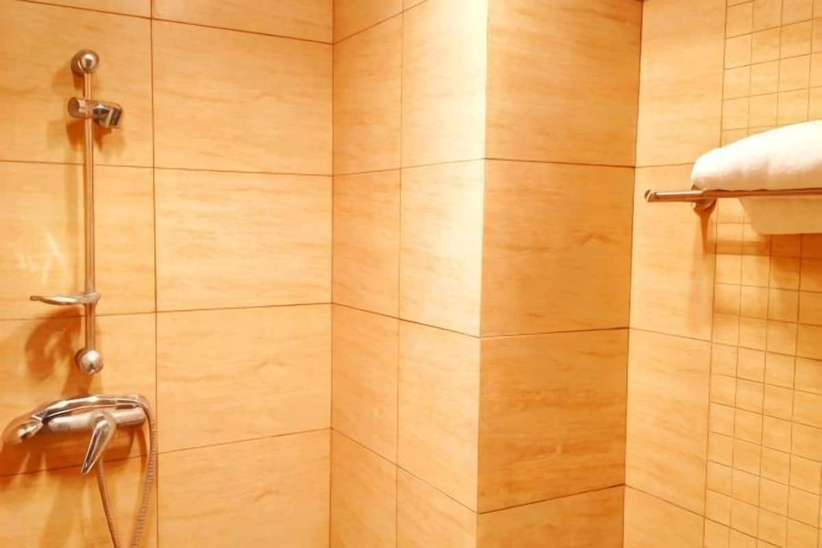 A bathroom with a shower, a towel rack, and a tiled wall.