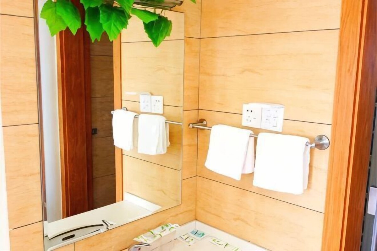A bathroom with a wooden wall, a mirror, a towel rack, and a shower.