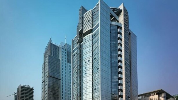 Un immeuble de grande hauteur doté d’une architecture moderne, caractérisé par une structure triangulaire imposante au sommet et de nombreux balcons.