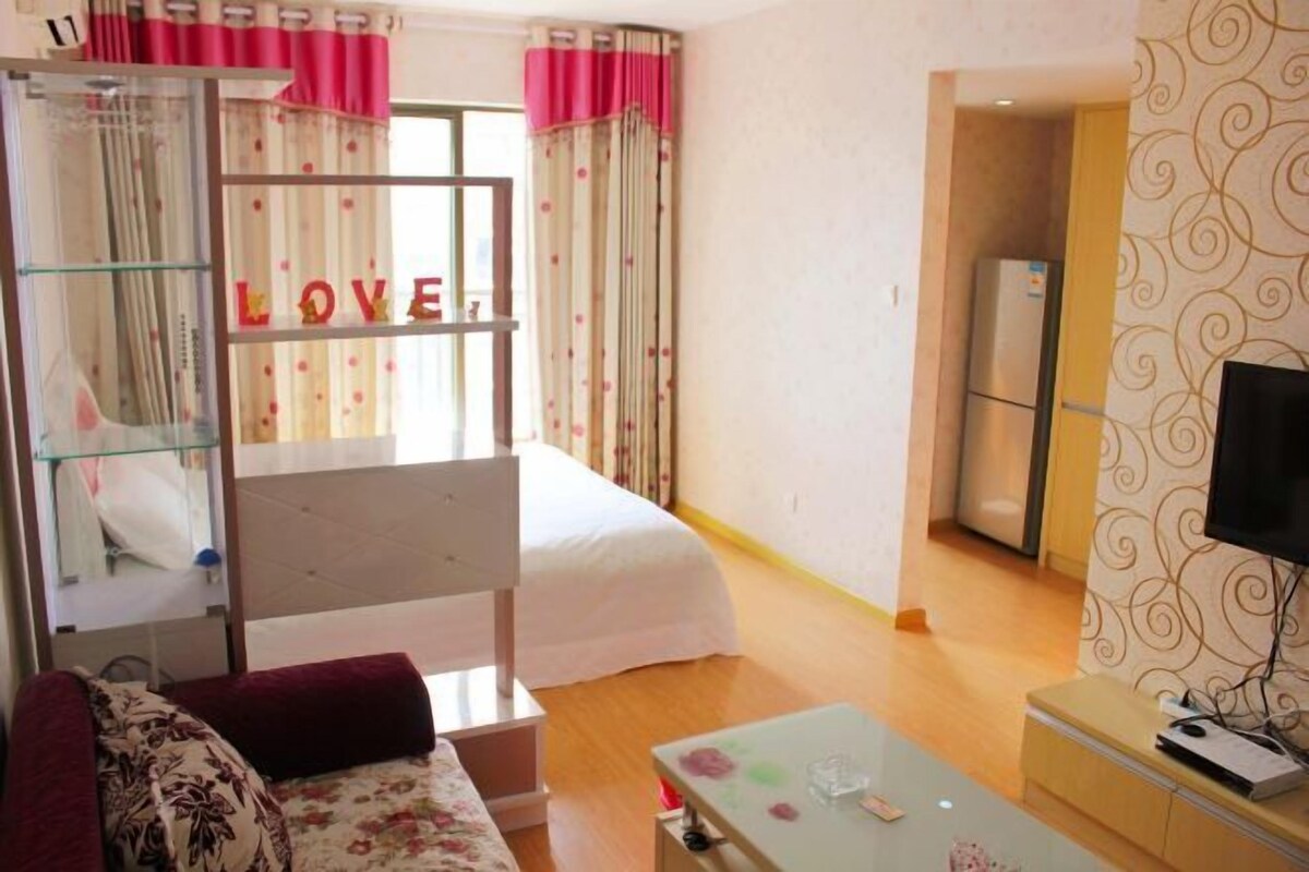 A bedroom with a bed, a TV, a glass partition with 'LOVE' letters, and a wardrobe.