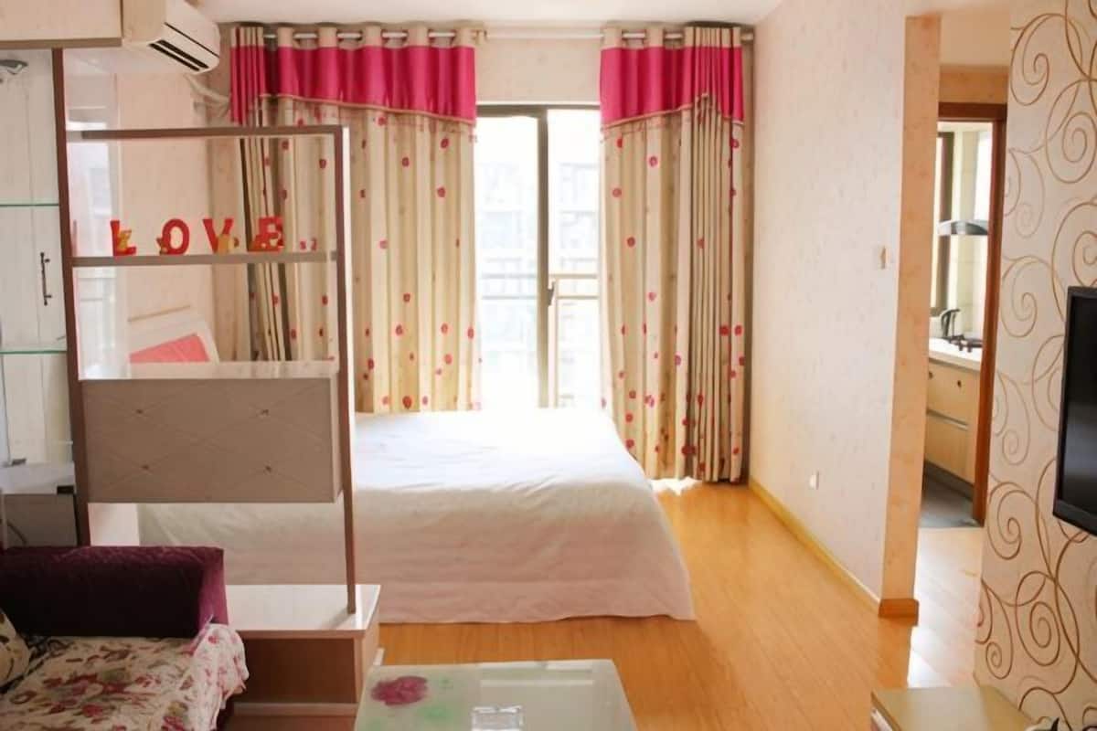 A bedroom with a bed, a desk, a chair, a TV, and a wardrobe.