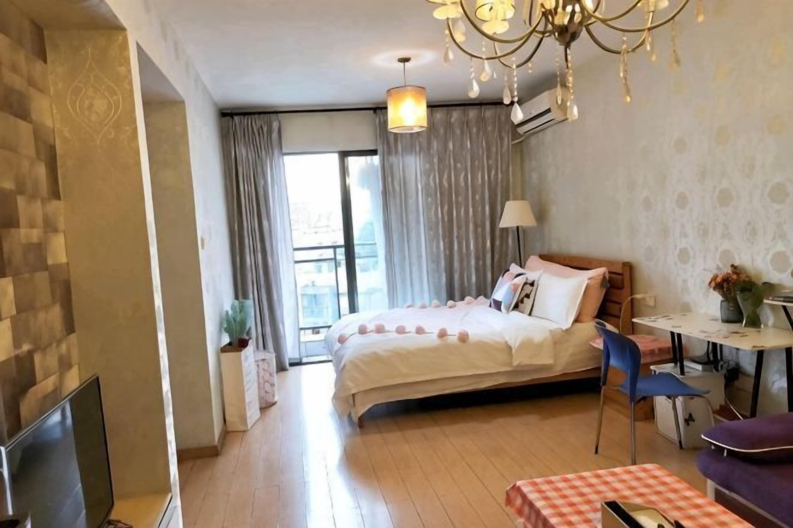 Ein Hotelzimmer mit Bett, Schreibtisch, Stuhl, Fernseher und einem Balkon.
