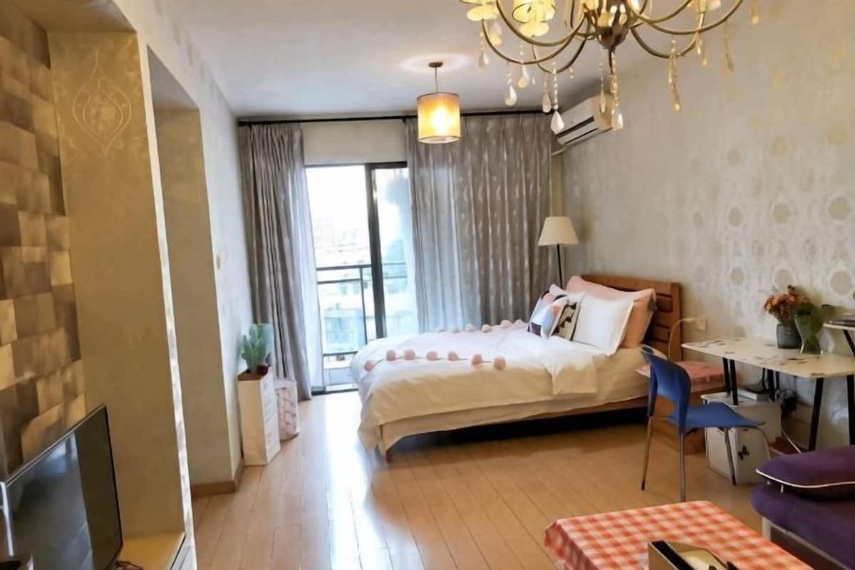 A hotel room with a bed, a desk, a chair, a TV, and a balcony.