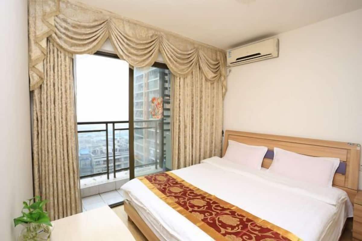 A hotel room with a large bed, a window with curtains, and an air conditioning unit on the wall.