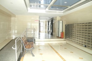 A hallway with a bench, a row of lockers, and a glass ceiling.