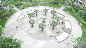 Une place circulaire avec une fontaine centrale, entourée de palmiers et de bancs.