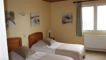 A room with two beds, a radiator, and artwork on the walls.