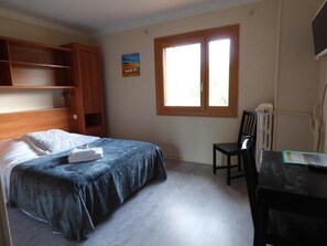 A bedroom with a bed, a desk, a chair, and a window. - Logis Hotel La Cremaillere St Bonnet (Saint-Bonnet-en-Champsaur)