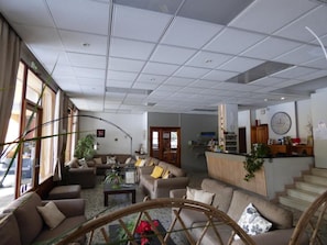 Ein geräumiger Wohnbereich mit mehreren Sofas, einem Couchtisch und einem Essbereich. Eine Treppe führt zu einer oberen Ebene.
