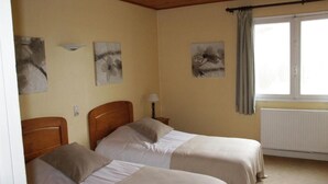 Una habitación con dos camas, un radiador y obras de arte en las paredes.