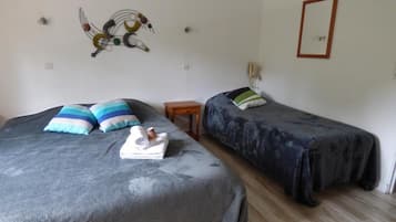 Una habitación con dos camas, cada una con un edredón de estampado diferente, una mesita de noche de madera y un cuadro decorativo en la pared.