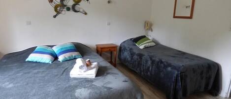 Una habitación con dos camas, cada una con un edredón de estampado diferente, una mesita de noche de madera y un cuadro decorativo en la pared.