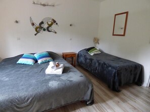 Una habitación con dos camas, cada una con un edredón de estampado diferente, una mesita de noche de madera y un cuadro decorativo en la pared.