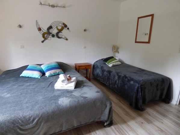 Una habitación con dos camas, cada una con un edredón de estampado diferente, una mesita de noche de madera y un cuadro decorativo en la pared.
