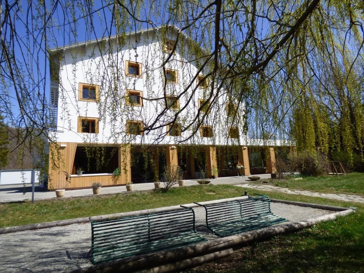 A building with a white facade, multiple windows, and a covered outdoor area with benches.