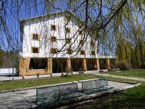 A building with a white facade, multiple windows, and a covered outdoor area with benches.