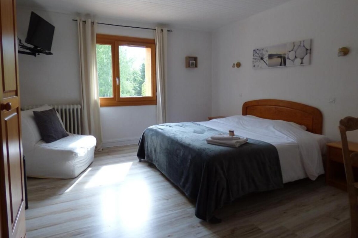 Un dormitorio con una cama, una silla, un radiador, una ventana y un televisor.