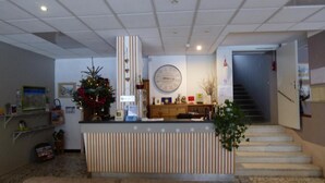 Zona de recepción con mostrador, reloj, escalera y un árbol de Navidad.