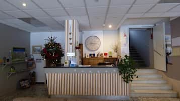 A reception area with a counter, a clock, a staircase, and a Christmas tree.