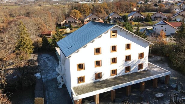 A white building with multiple windows and a sloped roof, surrounded by trees and a mountainous backdrop. - Logis Hotel La Cremaillere St Bonnet (Saint-Bonnet-en-Champsaur)