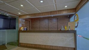 A reception desk with a wooden finish, a glass partition, and a wall-mounted sign with information. - Hotel Limra Surat (Surat)
