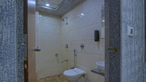 A bathroom with a toilet, bidet, and sink. - Hotel Limra Surat (Surat)