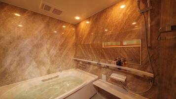 A bathroom with a marble wall, a bathtub, a shower, and a mirror.