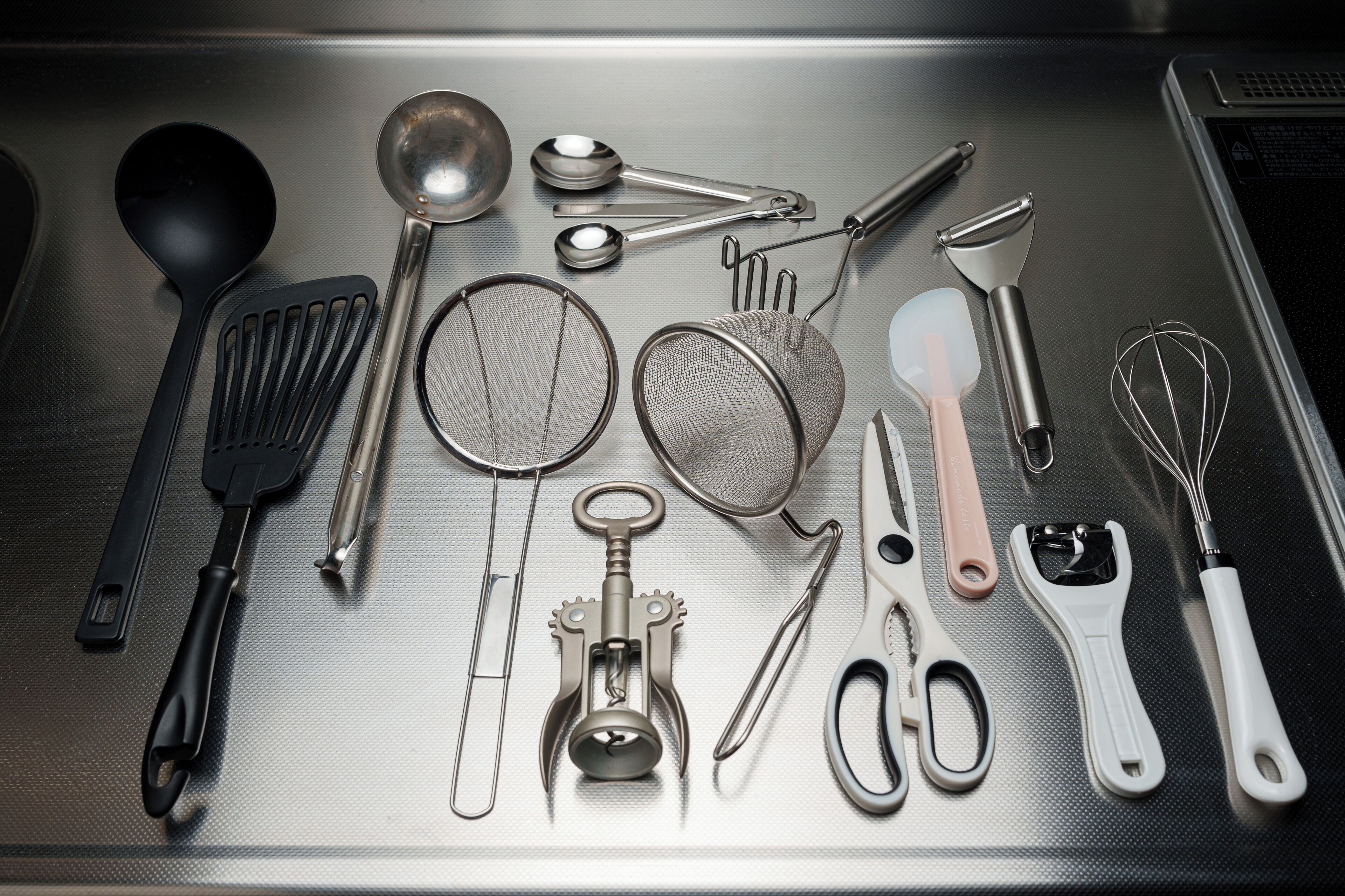 A stainless steel kitchen counter with various utensils and kitchen tools.