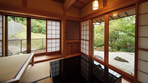 Une pièce de style japonais traditionnel, avec un sol recouvert de tatamis, des portes coulissantes en papier de riz (shoji) et une vue sur un jardin.