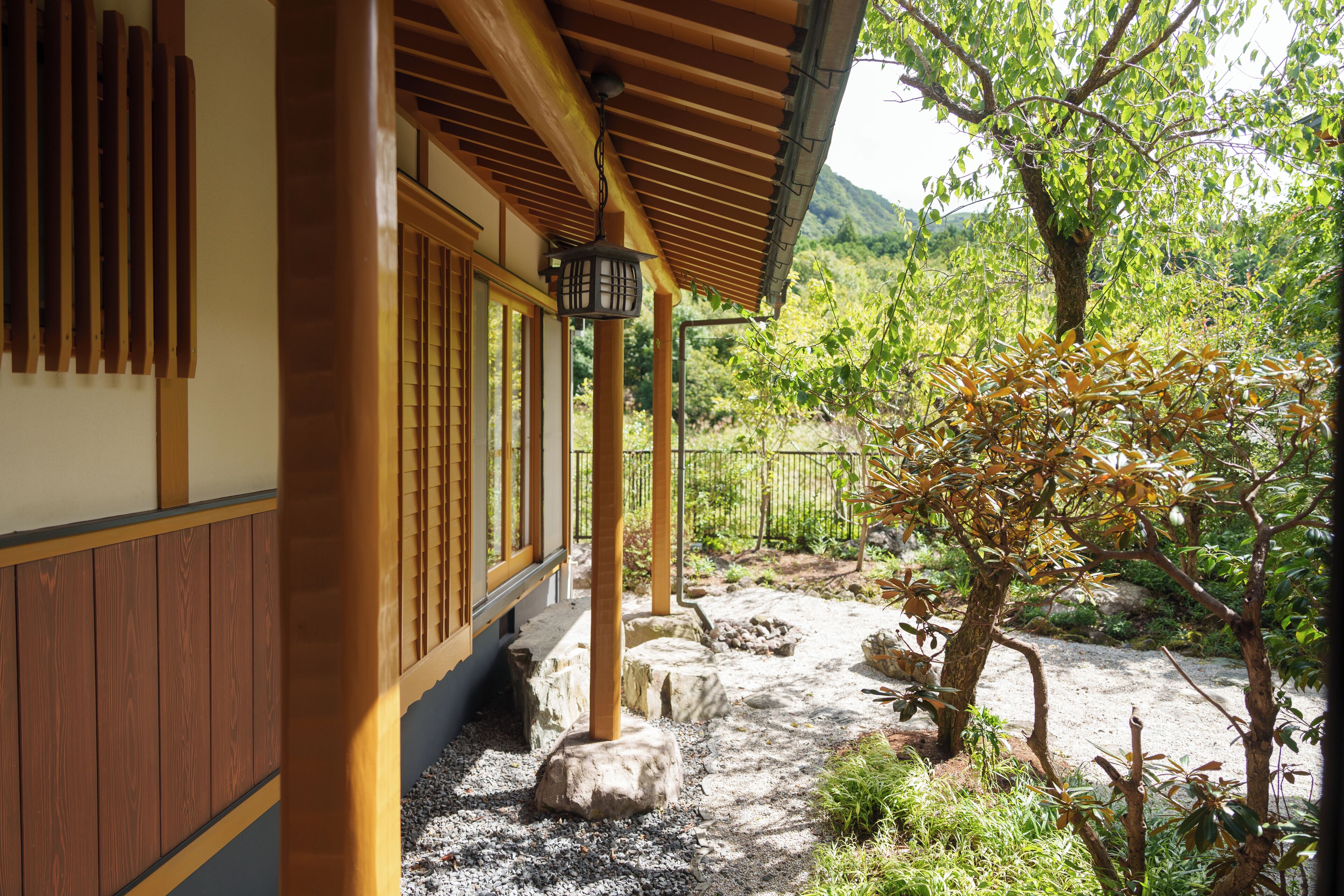 A traditional Japanese building with wooden beams and a tiled roof, surrounded by a garden with rocks and trees.