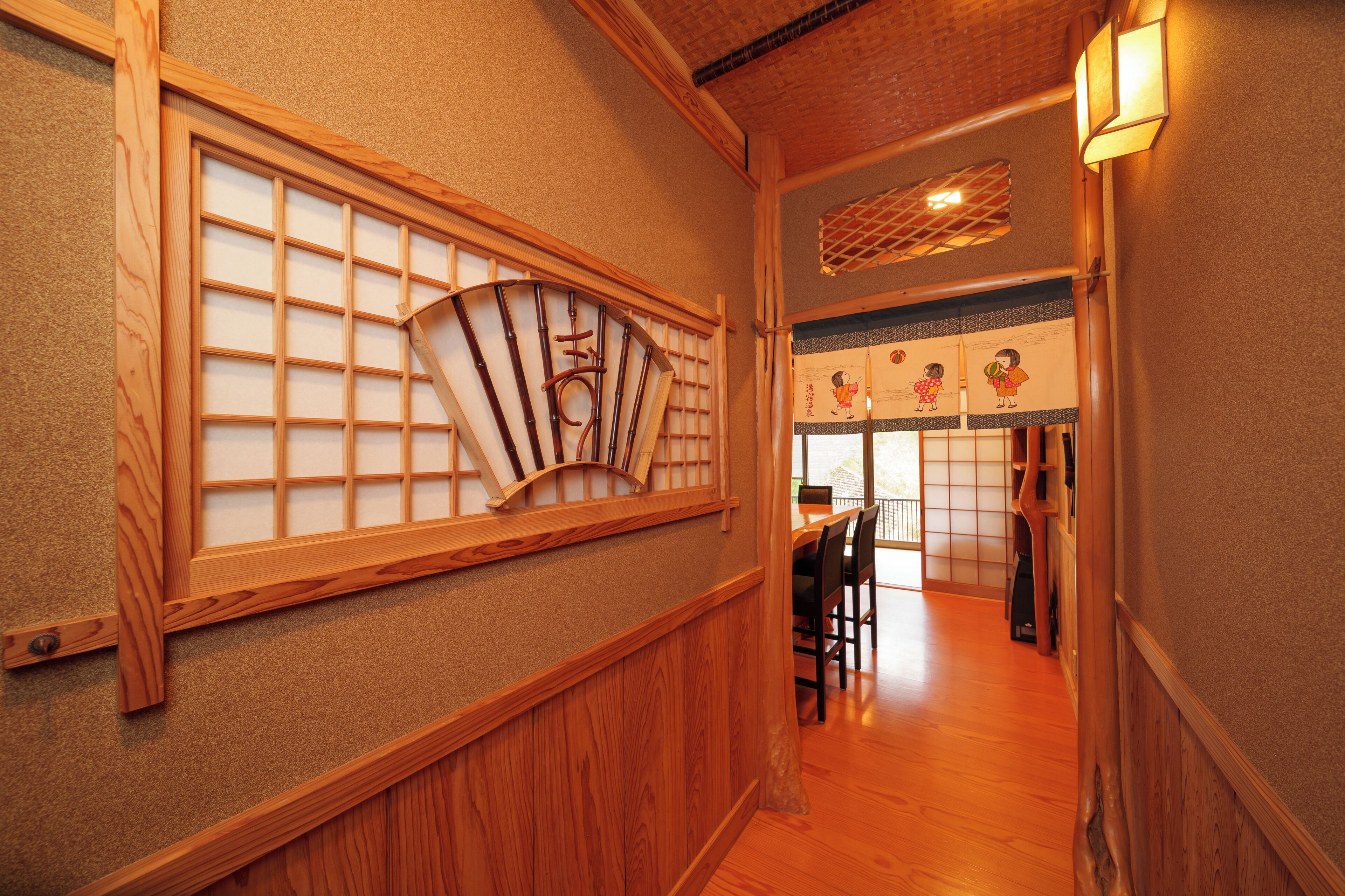 A traditional Japanese interior with wooden sliding doors, a dining area with chairs, and a view of a garden through a window.