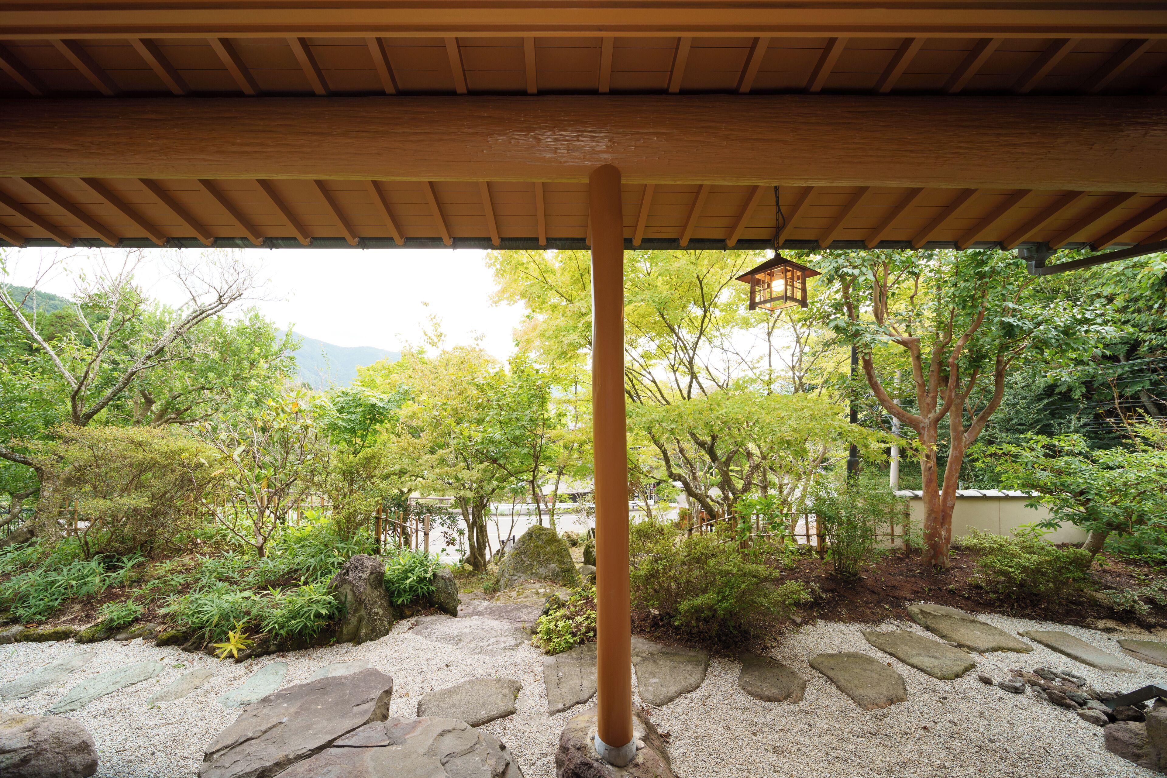 Un jardín japonés tradicional con un sendero de madera, escalones de piedra y un farol.