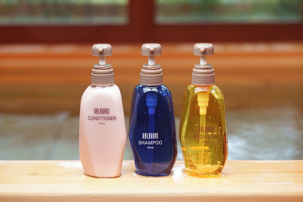 Trois flacons de produits de soins capillaires sur une surface en bois.