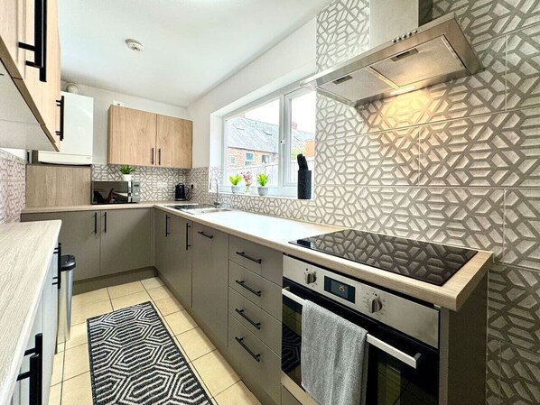A modern kitchen with a built-in stove, a window, and patterned backsplash.