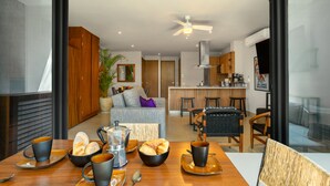Eine moderne Küche mit Essbereich, mit einem Holztisch, der für das Frühstück gedeckt ist, mit Tassen, Schüsseln und einer Kaffeekanne.
