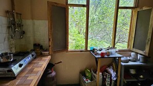 Une petite cuisine équipée d’une cuisinière à gaz, d’une fenêtre et de divers ustensiles de cuisine.