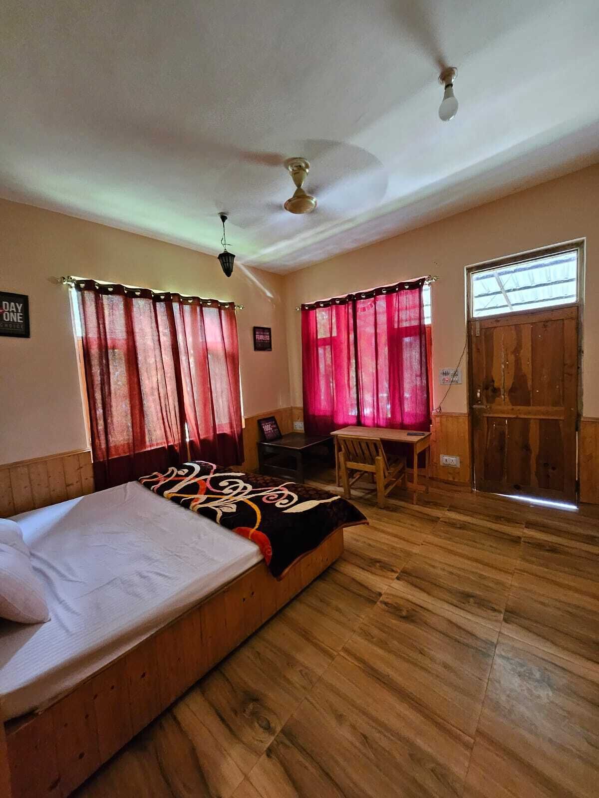 A room with a bed, a desk, a chair, a ceiling fan, and a window with curtains.