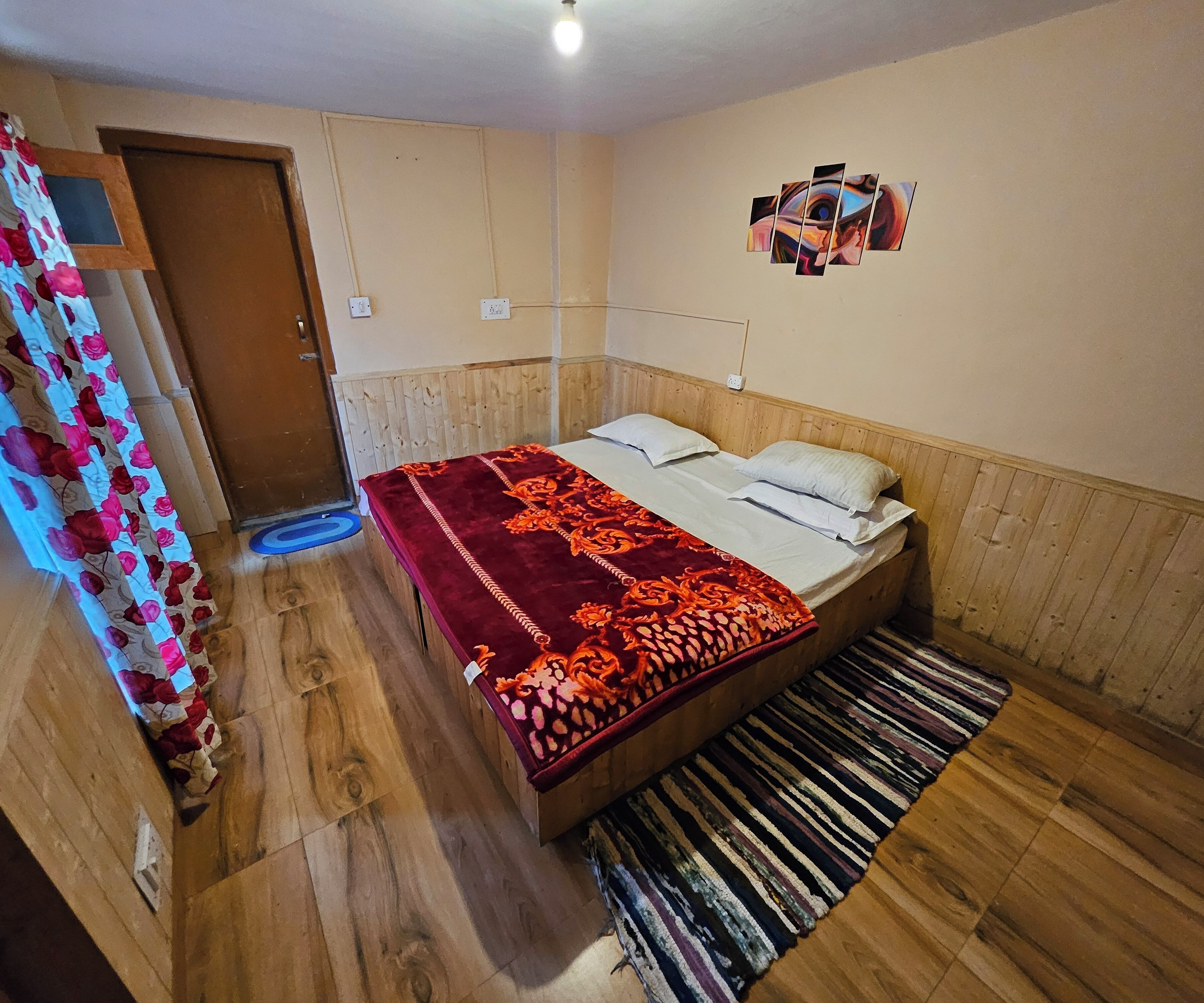 Ein Zimmer mit einem Holzbett, einem gemusterten Teppich und einem an der Wand befestigten Kunstwerk.