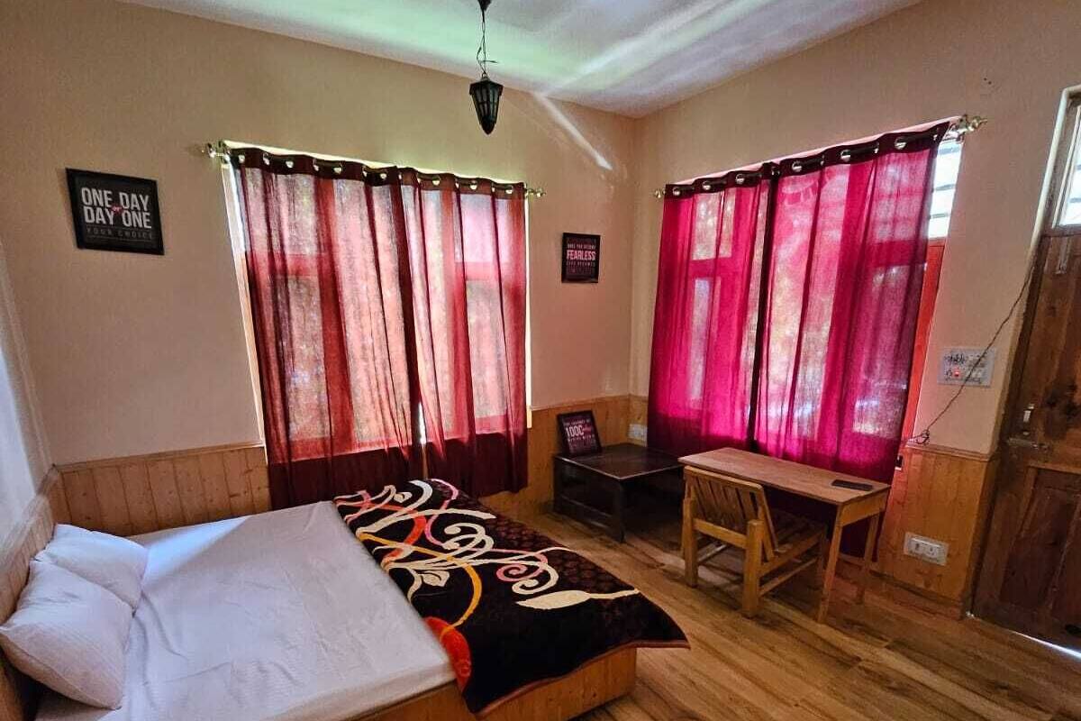 Une chambre à coucher avec un lit, un bureau et deux fenêtres avec des rideaux.