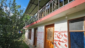 Un bâtiment à la façade rouge et blanche, doté de nombreuses portes et d’un balcon orné de rampes en métal.