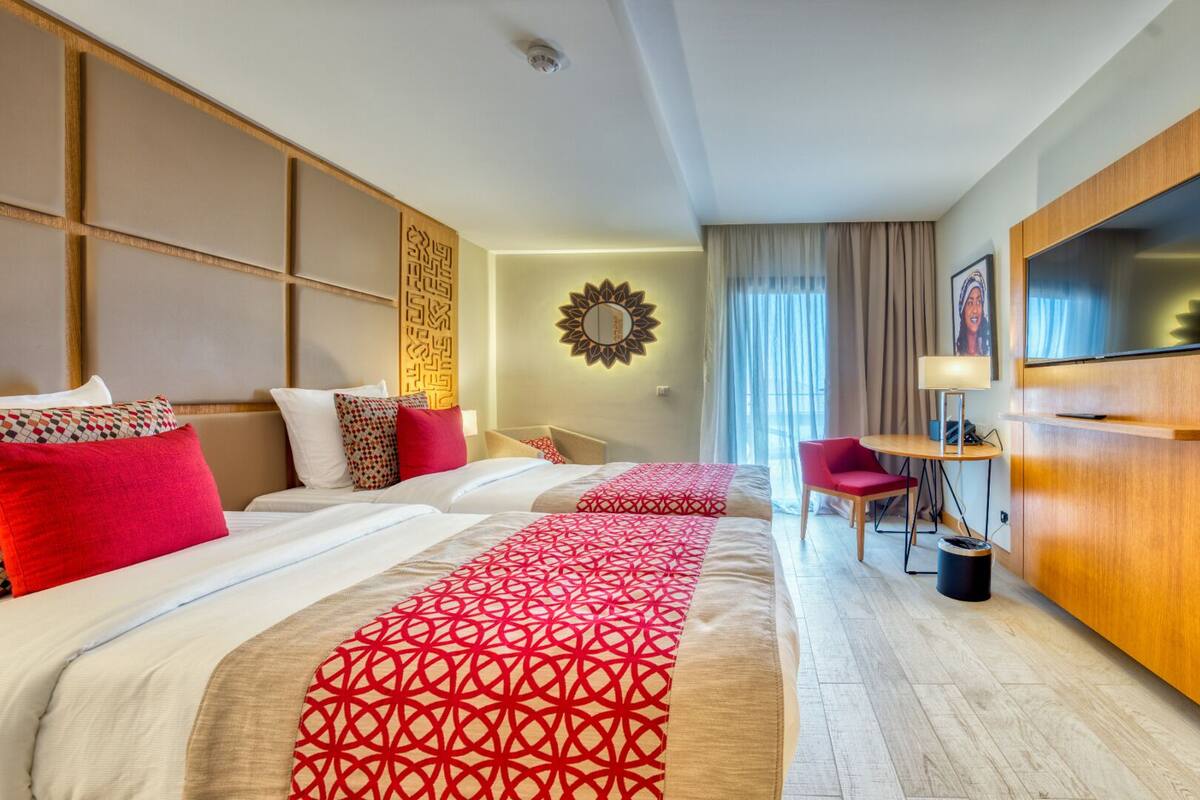 A hotel room with two beds, a TV, a desk, and a wardrobe.