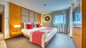 A hotel room with a large bed, a wooden headboard, a wall-mounted TV, and a view of the outdoors through sheer curtains. - Azalai Hôtel Dakar (Dakar)