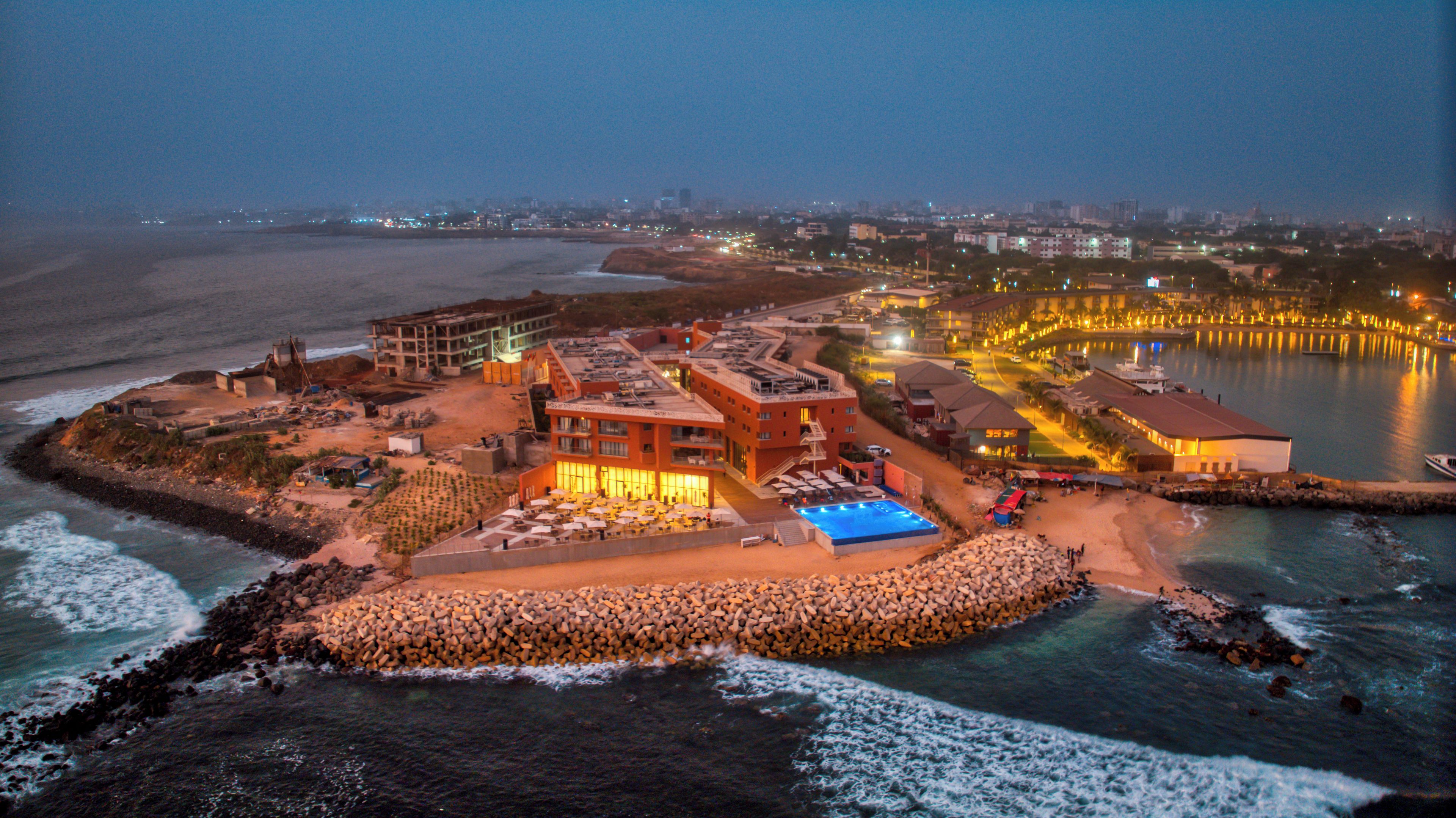 An aerial view of a coastal hotel with multiple buildings, a swimming pool, and a beach area.