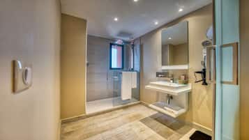 Un baño moderno con cabina de ducha de vidrio, un espejo grande y un lavabo blanco.
