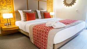 A hotel room with a neatly made bed, a bedside table with a lamp, and a decorative wall panel. - Azalai Hôtel Dakar (Dakar)