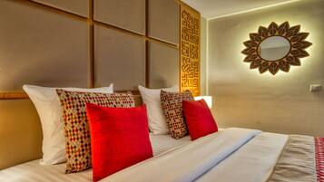 A hotel room with a bed, pillows, a wall-mounted mirror, and a decorative panel.