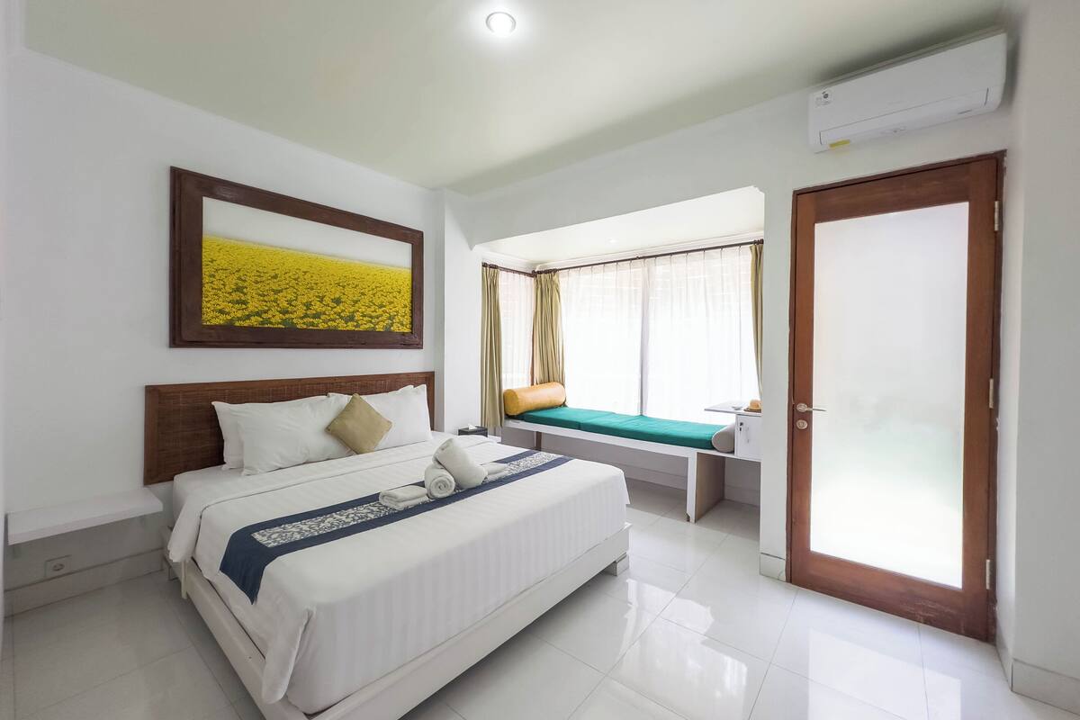 Une chambre d’hôtel avec un lit, une fenêtre avec des rideaux, une porte et un appareil de climatisation.